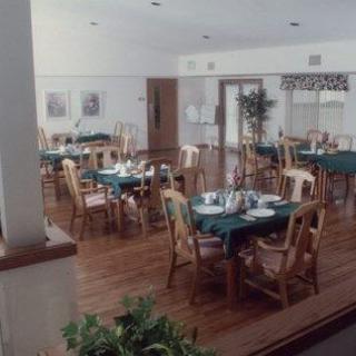An empty dining room with neatly arranged tables and chairs on a wooden floor.
