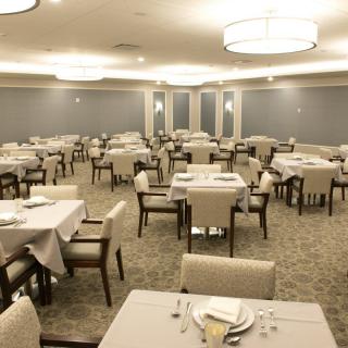 An elegant dining room with neatly arranged tables and chairs, featuring soft lighting and a spacious layout.