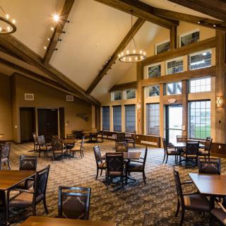 A cozy dining area with wooden beams, tables, and large windows.