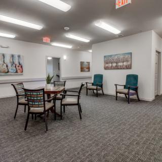 A well-lit room with a table and chairs, featuring artwork on the walls.