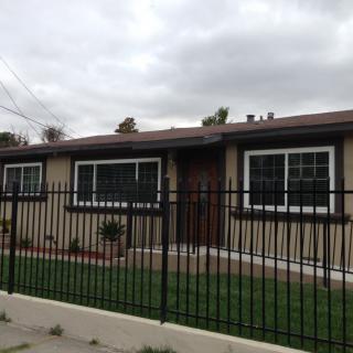 A single-story house with a fenced front yard and large windows.