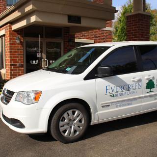A white van with a company logo parked in front of a building entrance.
