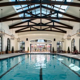 A luxurious indoor swimming pool with a glass ceiling and elegant architectural design.