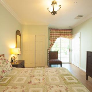 A cozy bedroom with a bed, bedside lamp, mirror, and closed curtains.