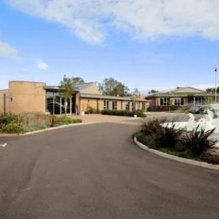 A modern building with a circular driveway under a clear sky.