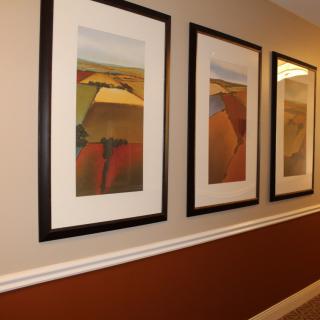 A hallway adorned with three abstract framed paintings in a row.