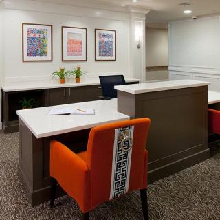 A modern office reception area featuring a clean, minimalist design with colorful artwork and comfortable seating.