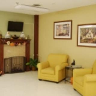 A cozy living room with yellow chairs, a decorated fireplace, and framed artwork on the walls.