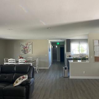 A modern open-plan living space featuring a comfortable leather couch, dining table set, and a kitchen area.