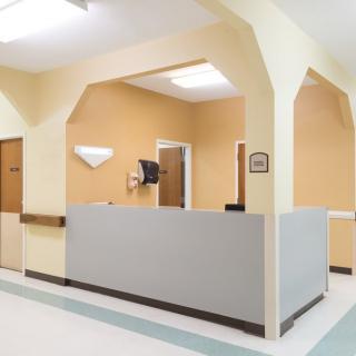 A reception area in a hospital with a front desk and beige walls.