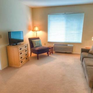 A cozy living room with a sofa, chair, television, and warm lighting.