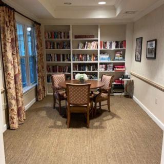 A cozy reading room with a round table and chairs, surrounded by bookshelves.