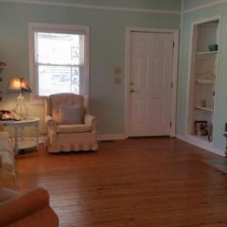 A cozy living room featuring a comfortable armchair, decorative lamp, and built-in bookshelf.