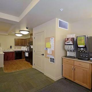 A cozy kitchen area featuring wooden cabinets, a coffee machine, and open space.