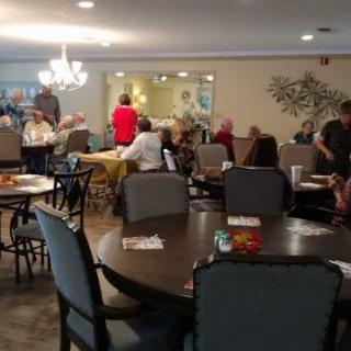 A group of people socializing in a dining area with tables and chairs.