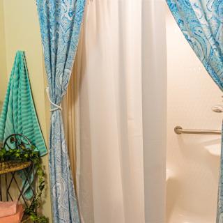 A cozy bathroom featuring a shower with elegant blue curtains and neatly arranged towels.