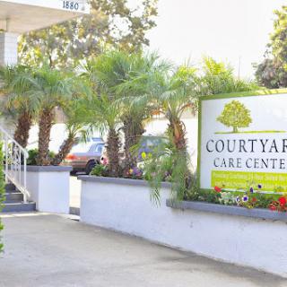 Entrance to Courtyard Care Center, featuring palm trees and welcoming signage.