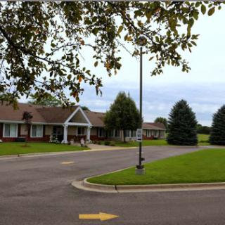 A peaceful residential area featuring well-maintained buildings and greenery under a cloudy sky.