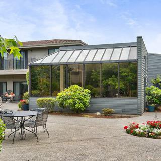 A modern home with a greenhouse extension and outdoor patio seating.