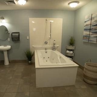 A modern bathroom with a large bathtub, sink, mirror, and decorative plants.