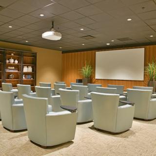 A modern conference room with comfortable seating and a projector screen.