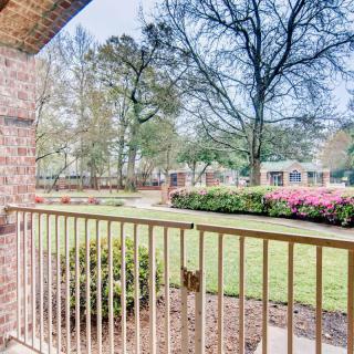 A view from the balcony overlooking a garden with trees and flowers.