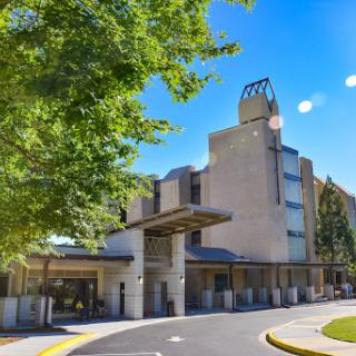 A modern hotel building set against a clear blue sky, surrounded by trees.