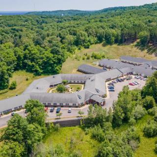 Aerial view of a building complex surrounded by lush greenery and forested countryside.
