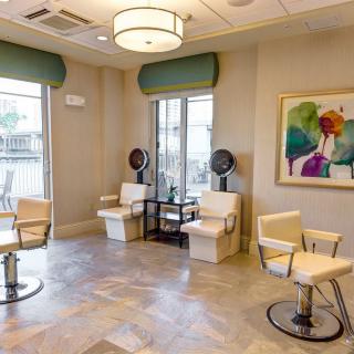 A brightly lit hair salon with stylish chairs, modern decor, and colorful artwork on the wall.