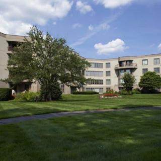 A grassy courtyard surrounded by a multi-story apartment building under a partly cloudy sky.