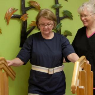 A person undergoing physical therapy with the assistance of a caregiver.