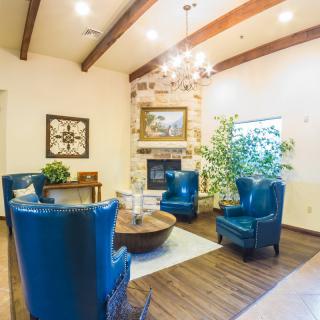 A cozy living room with blue chairs and a fireplace, featuring wooden floors and elegant decor.