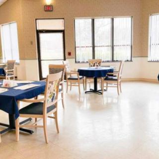 An empty dining area with tables and chairs, featuring large windows.