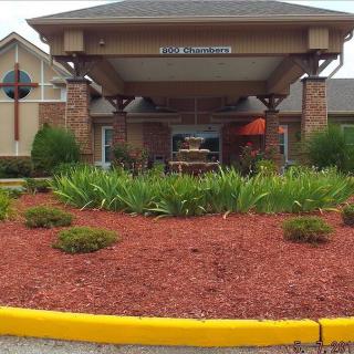 A well-maintained entrance to a building featuring red mulch and greenery.