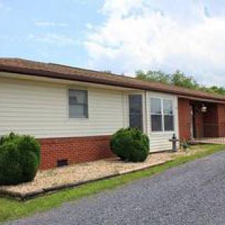 A single-story house with a combination of brick and siding exterior, featuring a driveway and landscaped bushes.