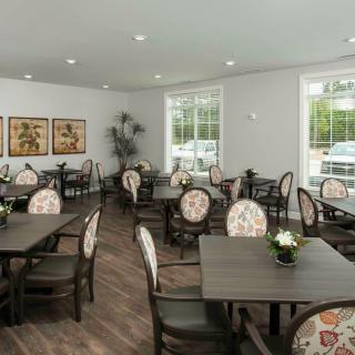 A spacious dining room with elegantly arranged tables and chairs, bright natural lighting, and tasteful decor.