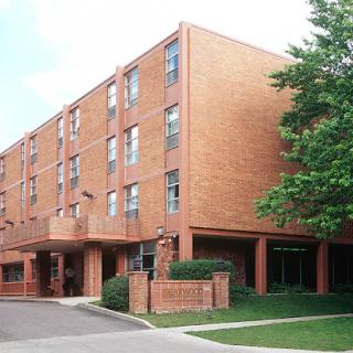 A multi-story brick apartment building surrounded by greenery.