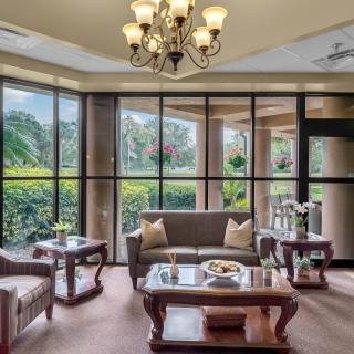 A spacious living room with large windows, elegant furniture, and a decorative chandelier.