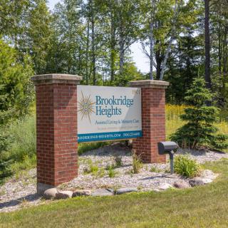 Entrance sign for Hawkridge Heights Assisted Living Community surrounded by trees and landscaping.