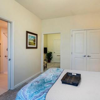 A cozy bedroom featuring a neatly made bed, artwork on the wall, and a closet with double doors.