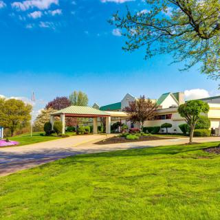 A scenic view of a building surrounded by lush greenery and a clear blue sky.