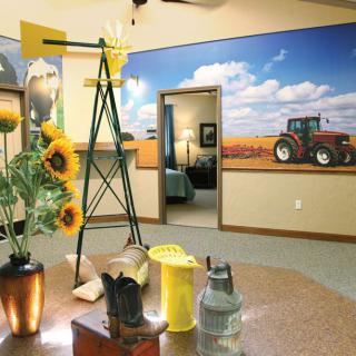 A farm-themed interior with sunflowers, a small windmill model, and a tractor mural on the wall.