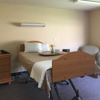 A hospital room with a single bed and basic furnishings.