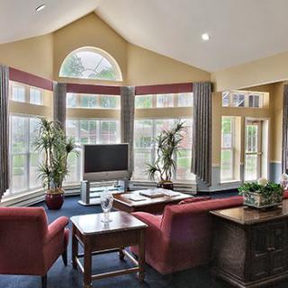 A spacious living room with large windows and vaulted ceilings, featuring comfortable seating and plenty of natural light.