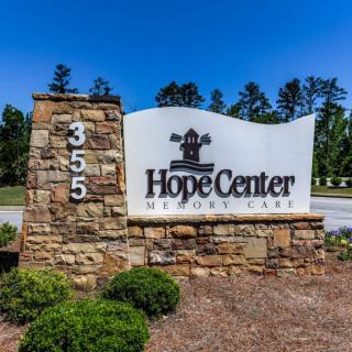 A stone sign marks the entrance to Hope Center, set against a backdrop of trees.