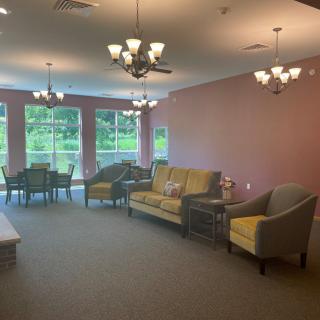 A cozy living room with sofas, armchairs, and large windows overlooking green scenery.