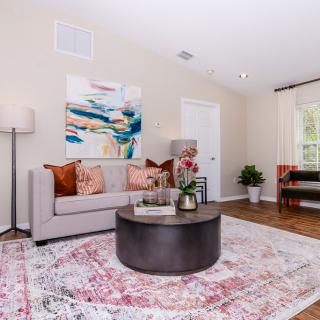 A cozy living room with a modern sofa, colorful artwork, and a round coffee table on a patterned rug.