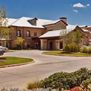 A modern residential building with a landscaped driveway.