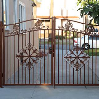 A beautifully designed wrought iron gate leading to a property.