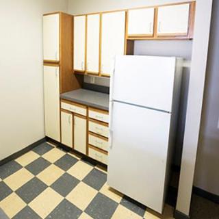 A retro-style kitchen with checkered flooring and white cabinets.